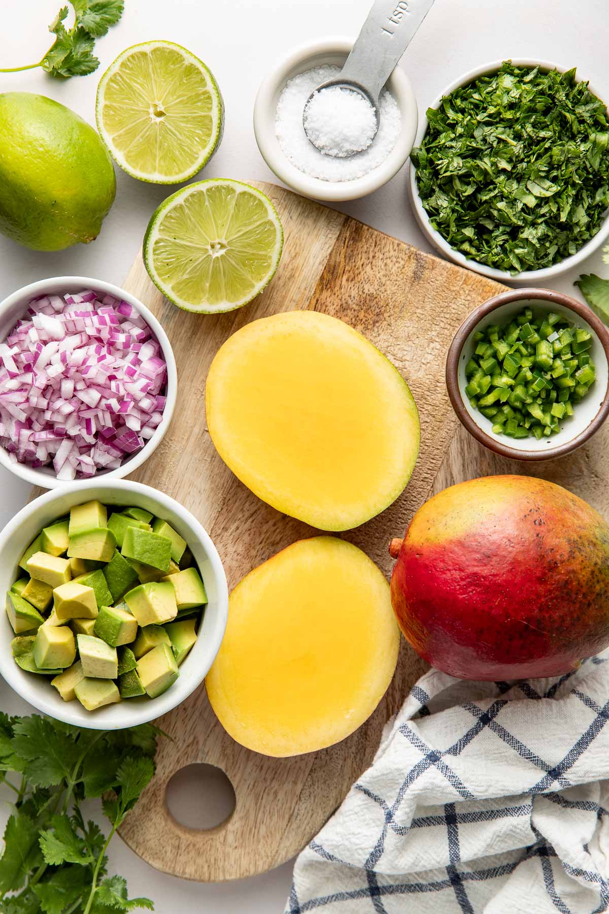 Overhead view of a variety of ingredients for Mango Salsa in different sized bowls.