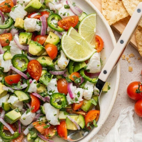 Overhead view of a bowl of fresh Ceviche garnished with limes.