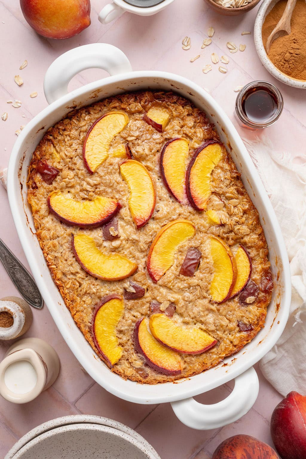 A rectangular baking dish full of peach baked oatmeal topped with peach slices.