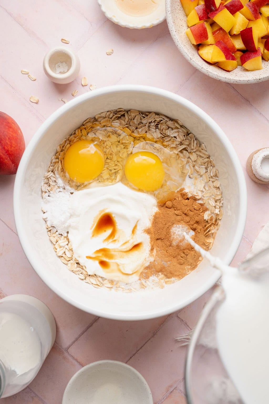 Wet ingredients being added to a bowl of oats to make peach baked oatmeal.