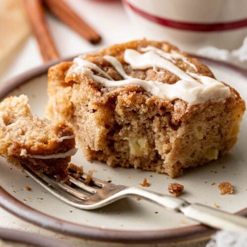 A square of apple coffee cake on a plate, a fork holding a bite.