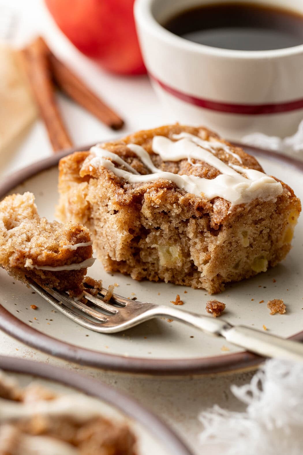 A slice of apple coffee cake on a plate, a fork holding a bite. 