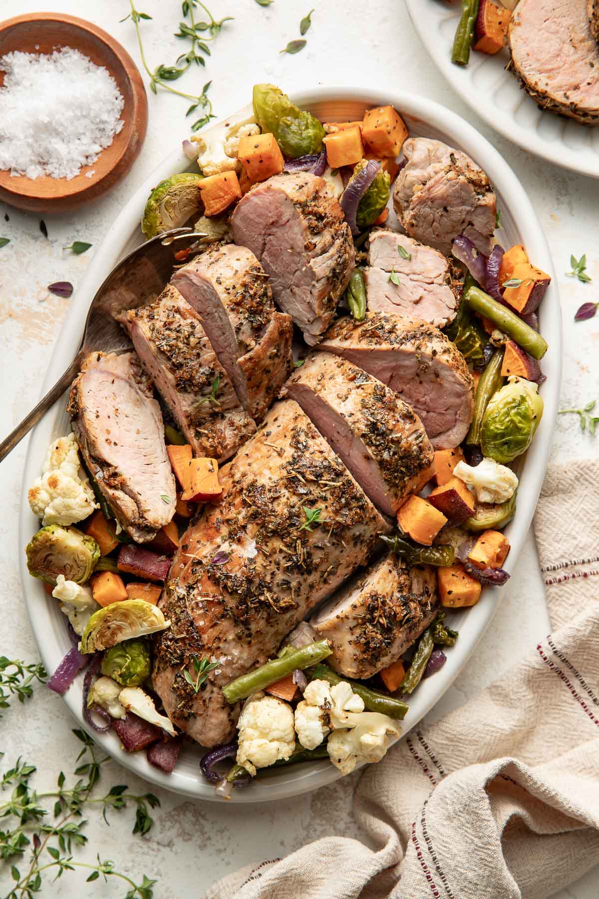 Oven roasted pork tenderloin on a platter with roasted vegetables.