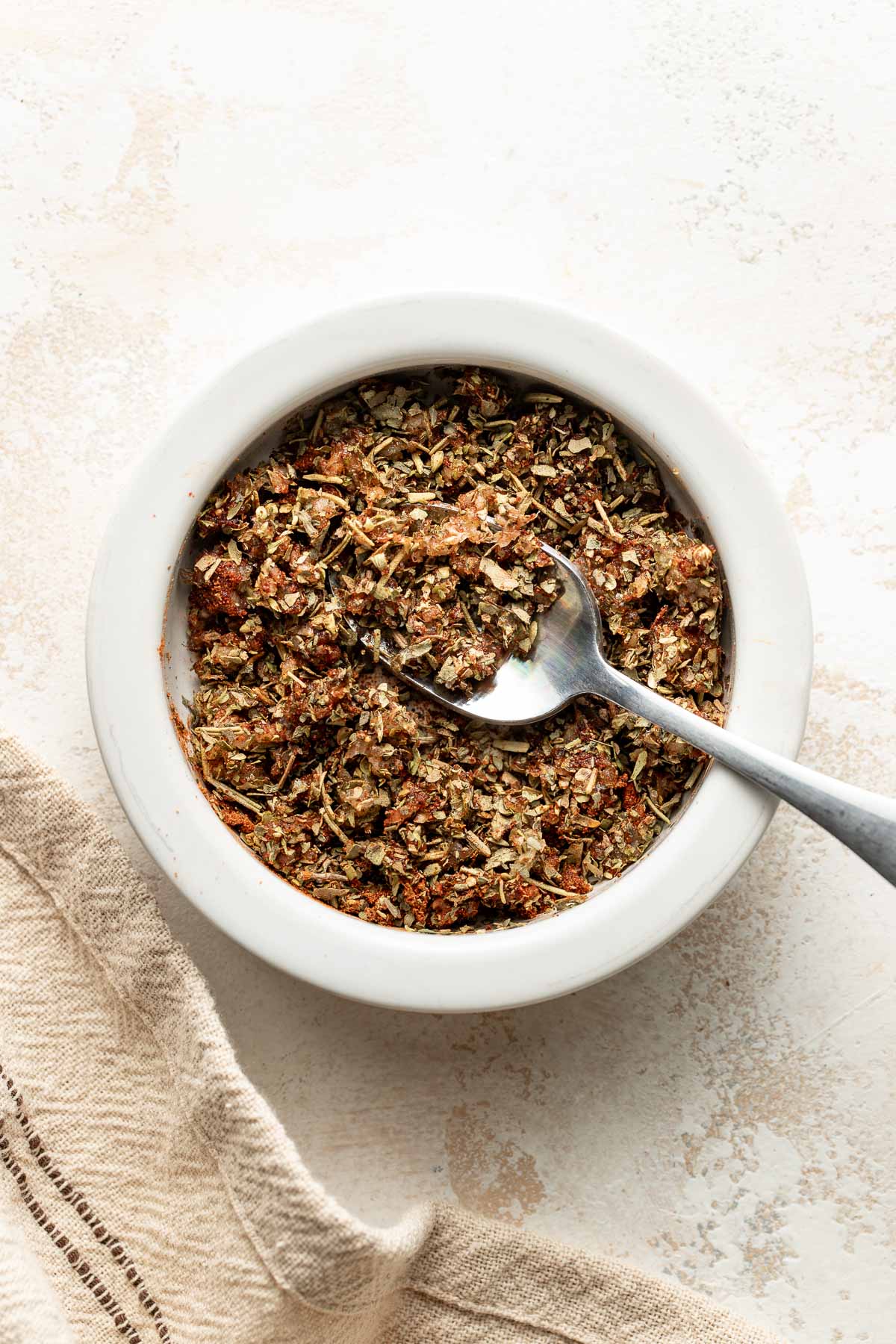A bowl of pork tenderloin rub, a spoon sticking out.