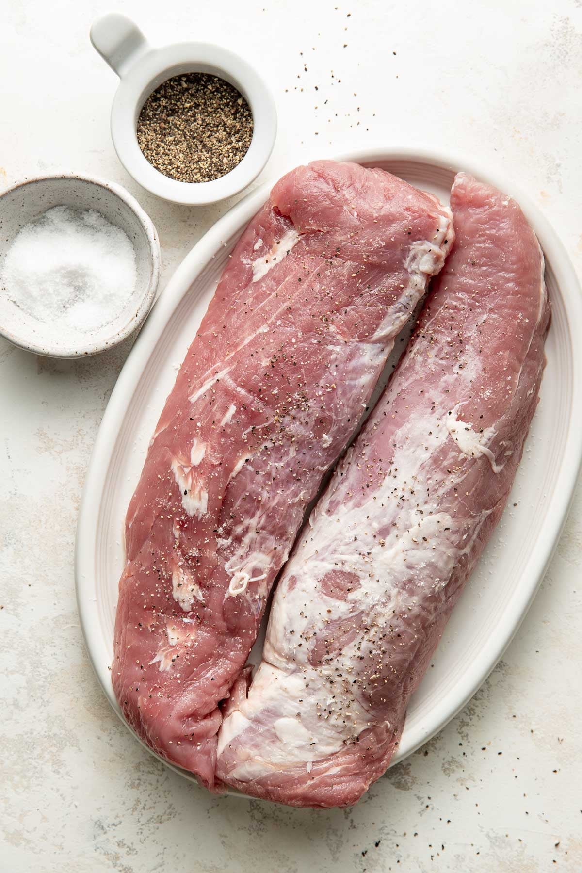 Two raw pork tenderloins on a plate.