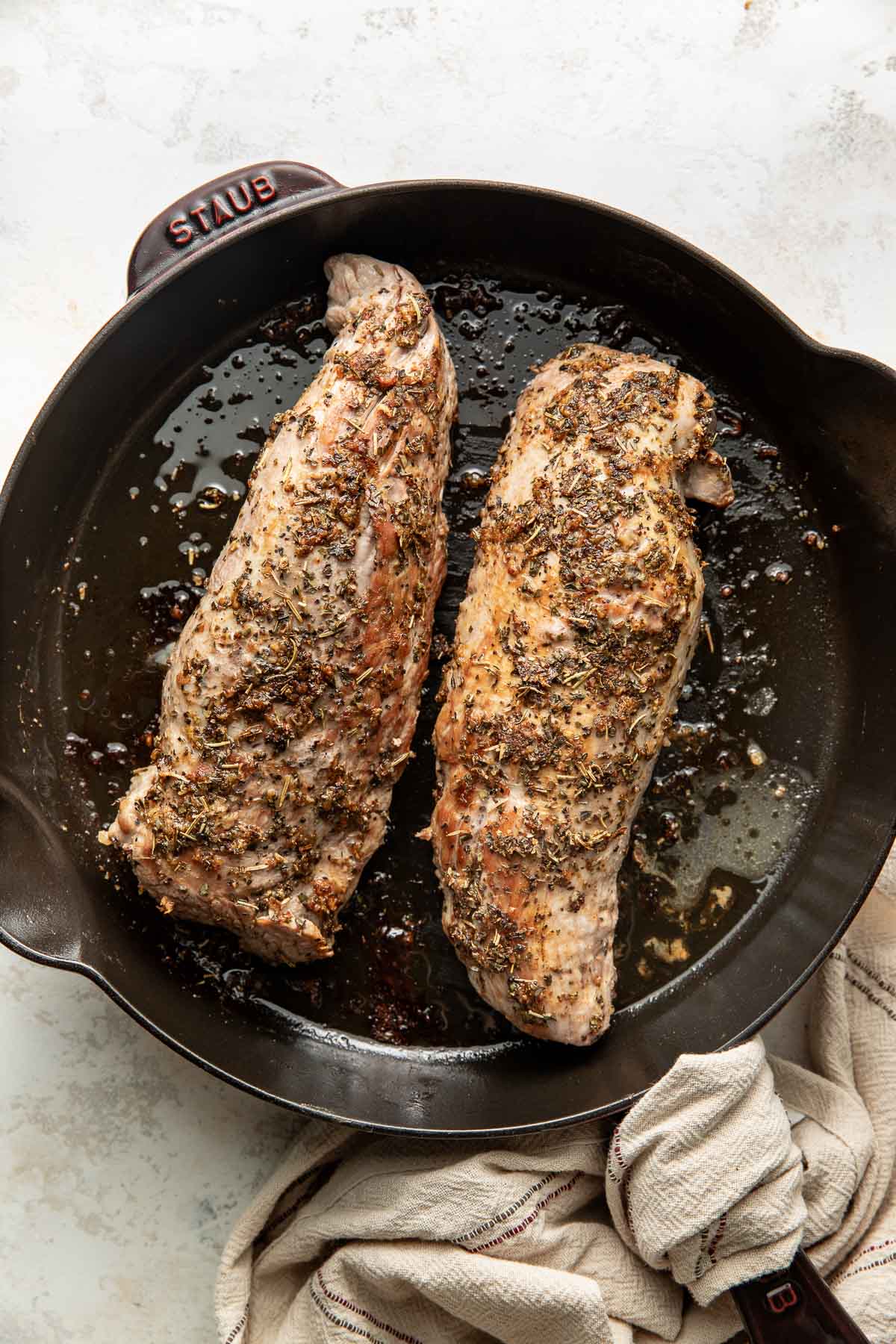 Two pork tenderloins in a cast-iron skillet.
