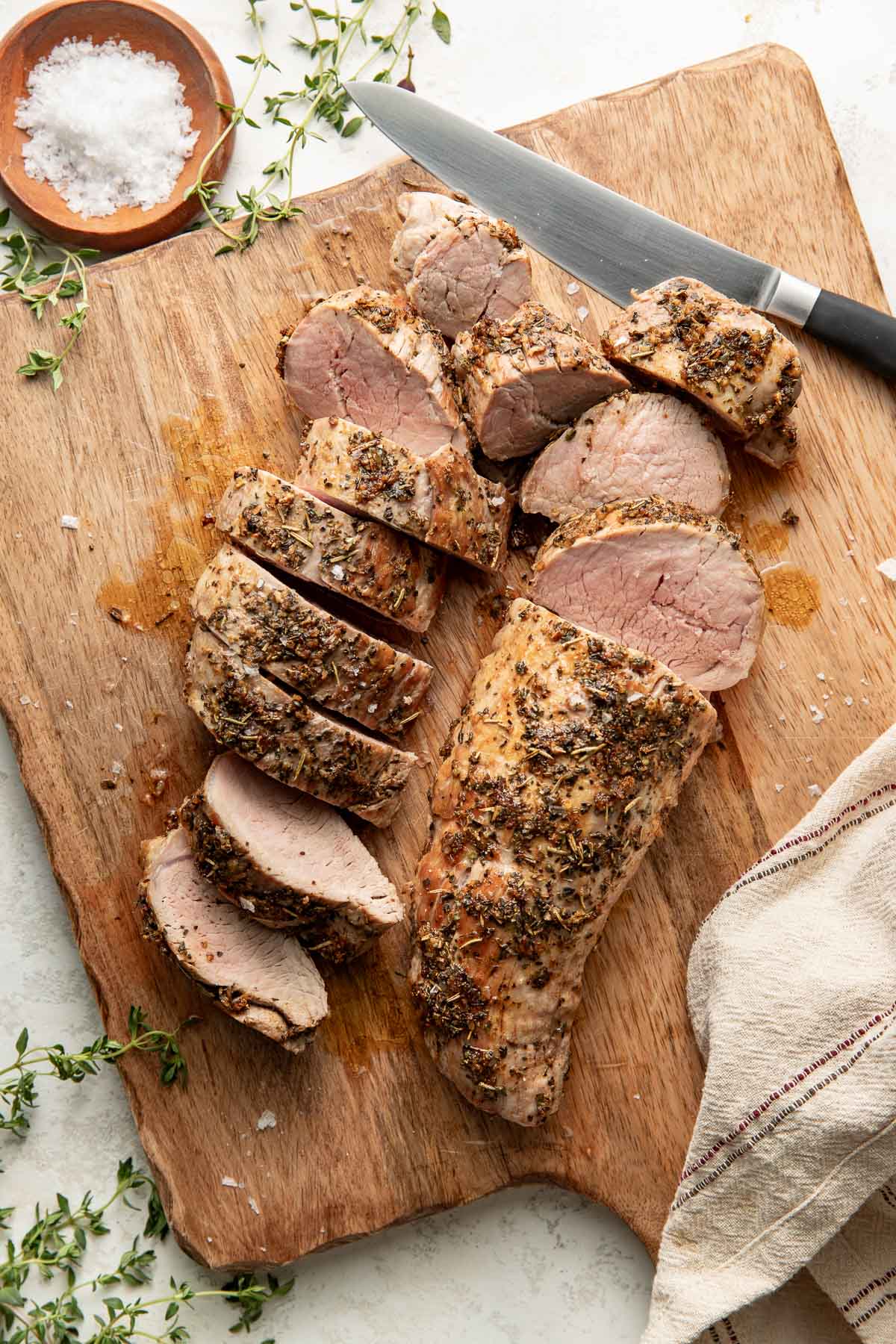 Sliced oven roasted pork tenderloin on a wooden cutting board.