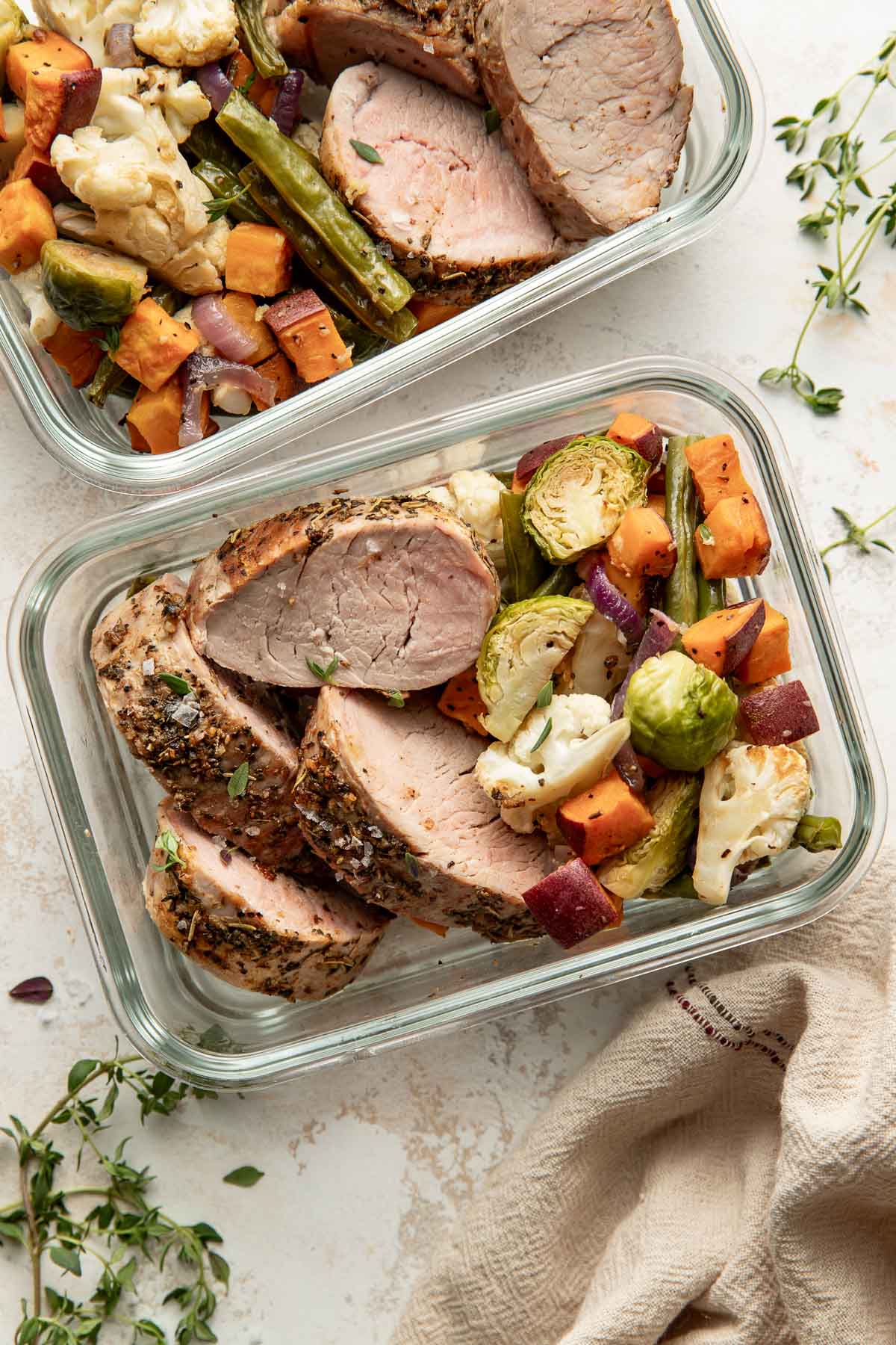 Oven roasted pork tenderloin slices and roasted vegetables in a meal prep container.