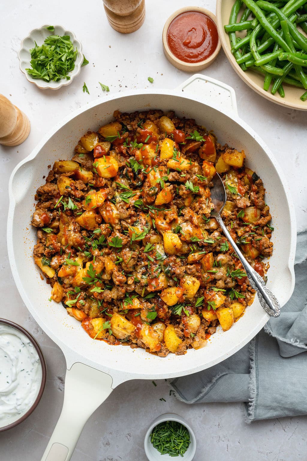 A ground beef and potatoes skillet with a spoon sticking out.