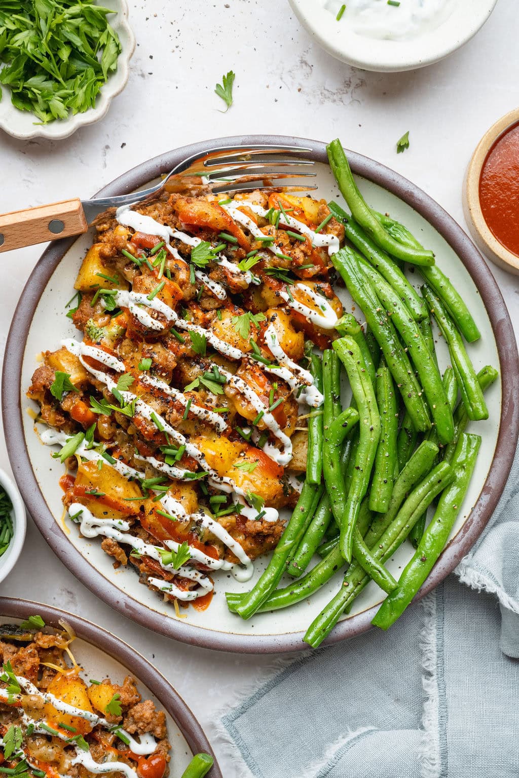 A plate of ground beef and potatoes and green beans, a fork on the side.