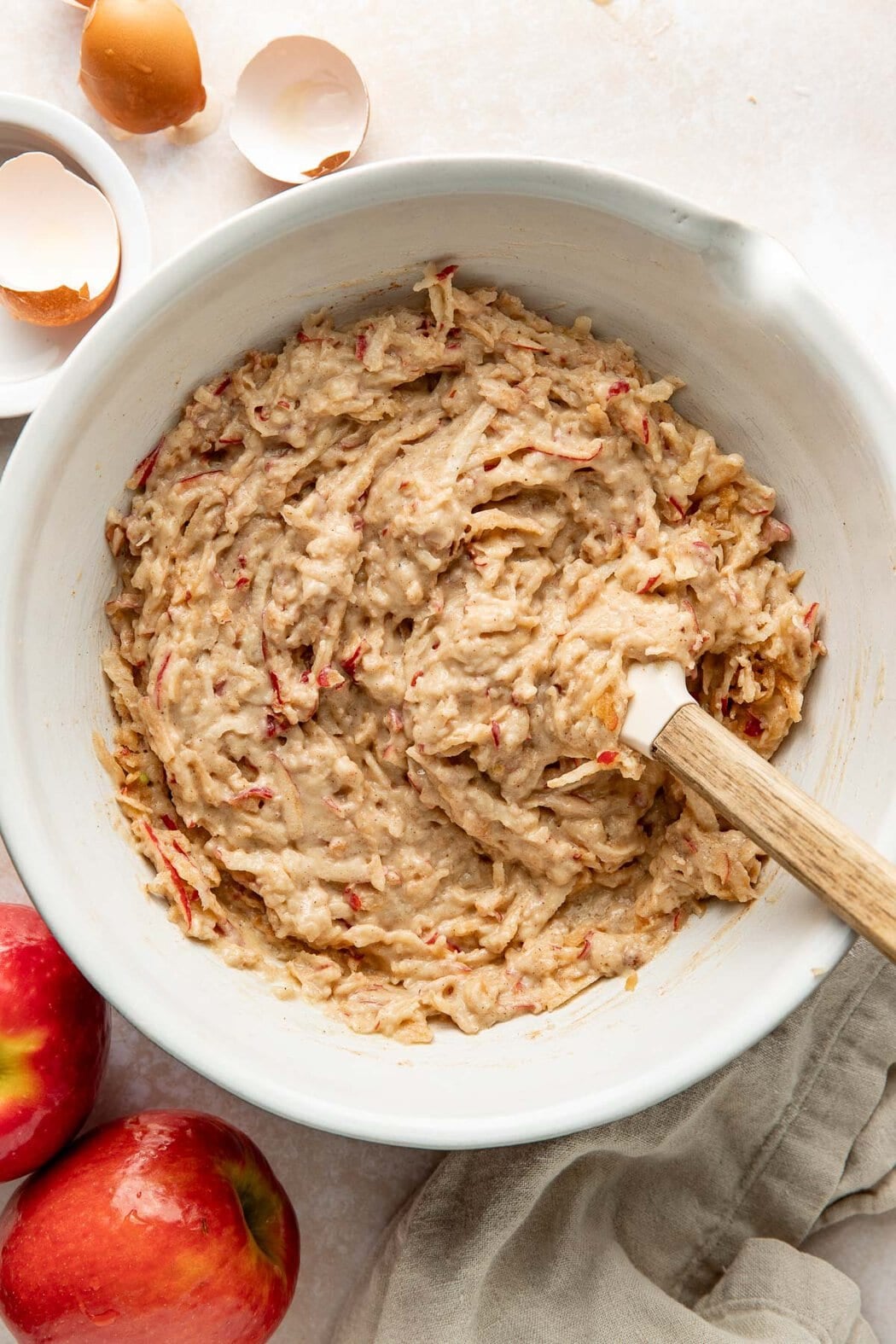 A spatula folding shredded apples into cake batter.