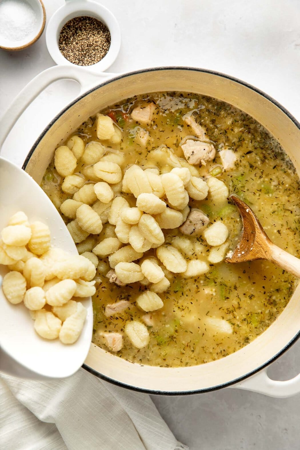 Gnocchi pieces being added to a pot of soup.