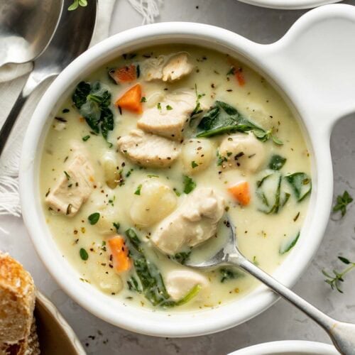 A bowl of chicken gnocchi soup with a spoon sticking out.