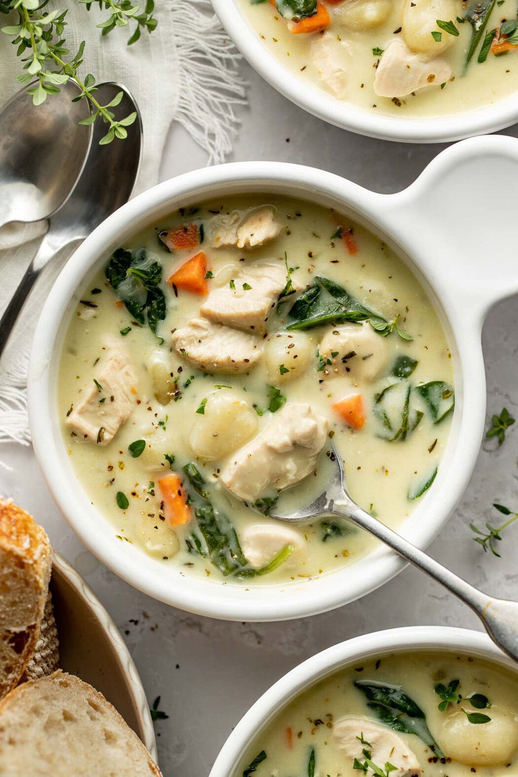 A bowl of chicken gnocchi soup with a spoon sticking out.