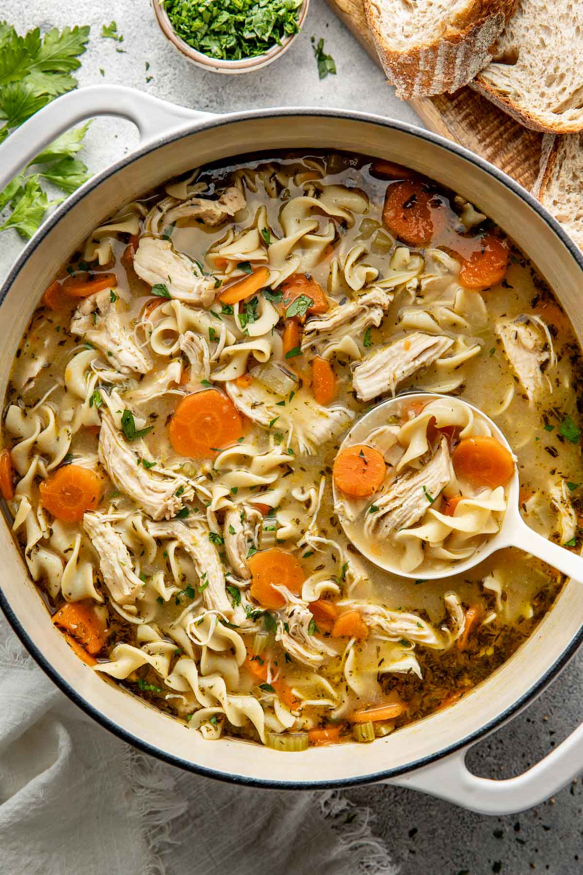 A pot of chicken noodle soup, a ladle lifting a scoop.