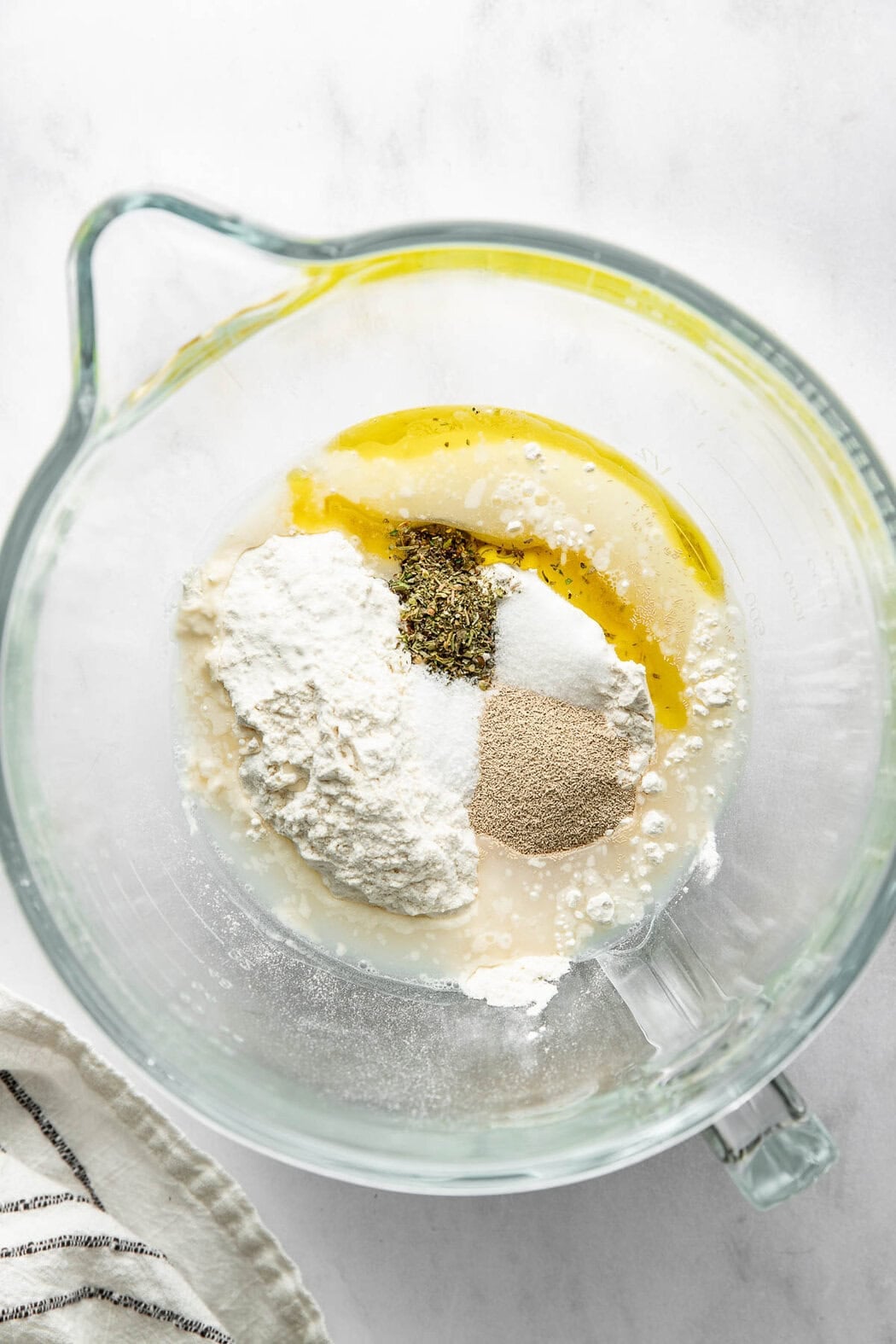 Homemade pizza dough ingredients in a glass measuring cup.