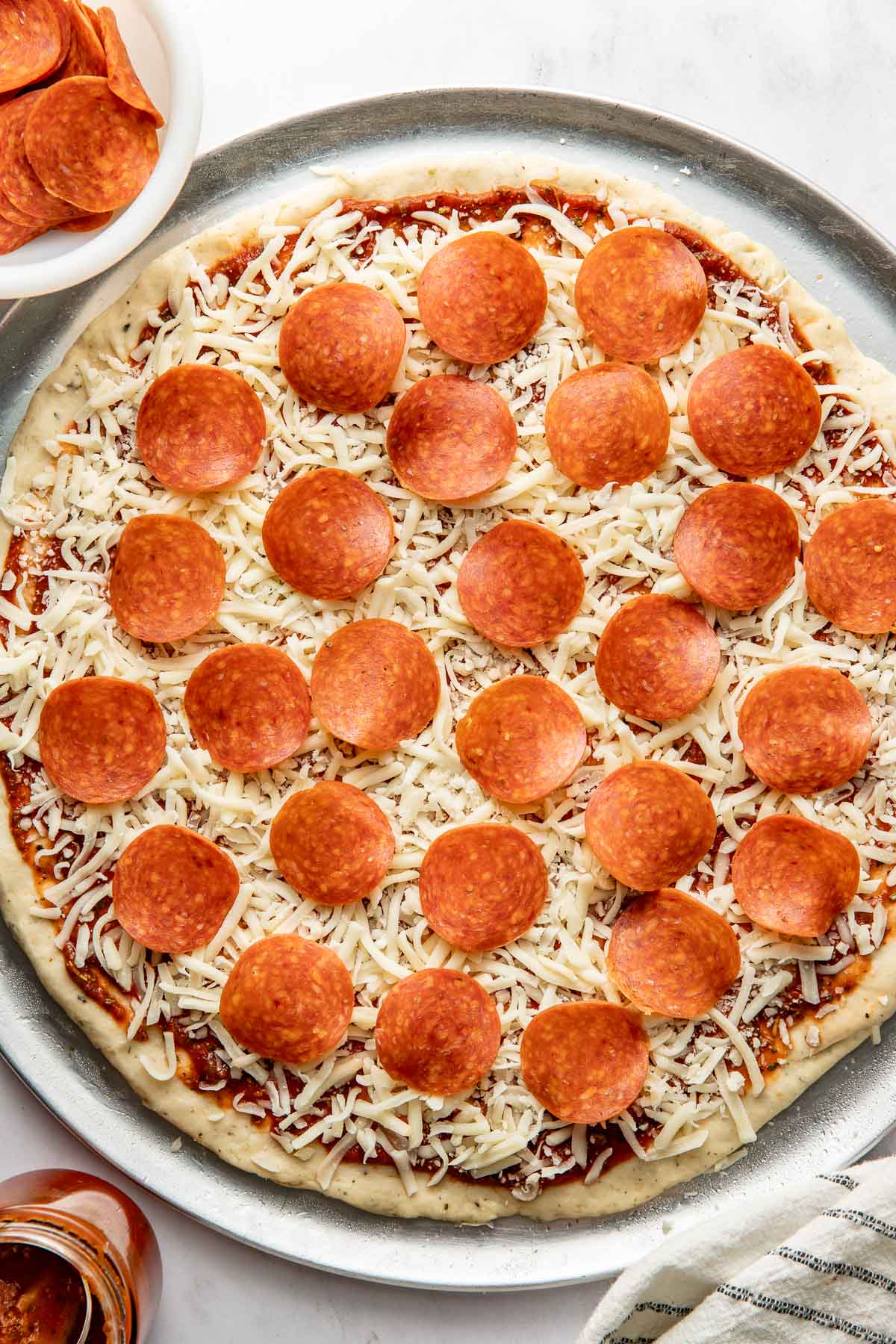 An uncooked pepperoni and cheese pizza with homemade pizza crust.