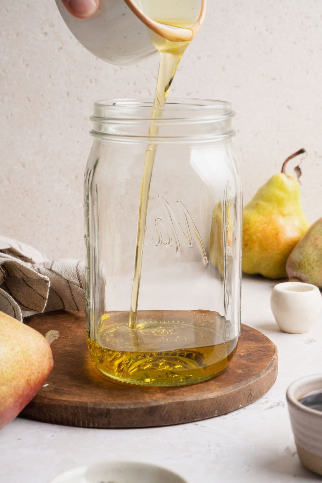 Olive oil being poured into a large mason jar.
