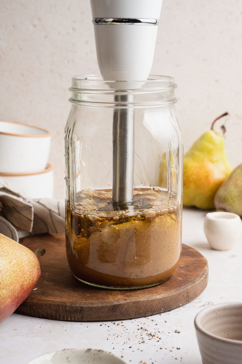 An immersion blender in a large mason jar blending balsamic vinaigrette.