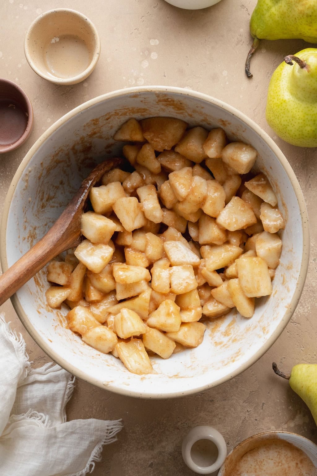 A bowl of spiced pears, a wooden spoon sticking out.