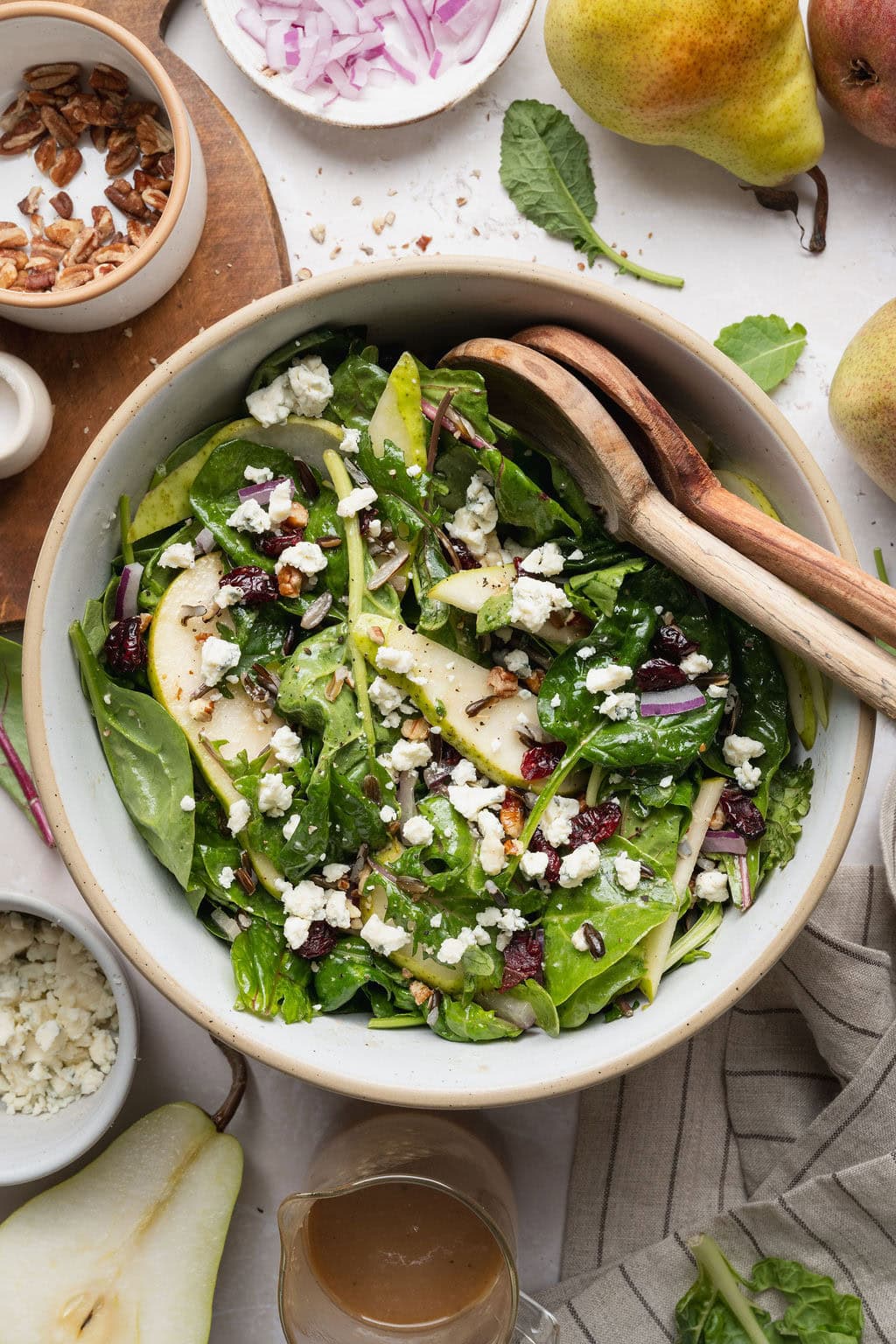 A bowl of pear salad with wooden serving spoons on the side.