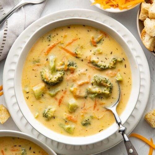 A bowl of broccoli cheddar soup with a spoon sticking out.