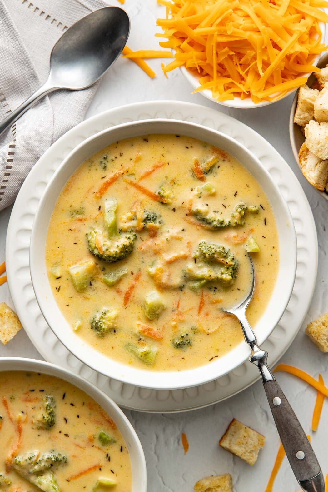 A bowl of broccoli cheddar soup with a spoon sticking out.