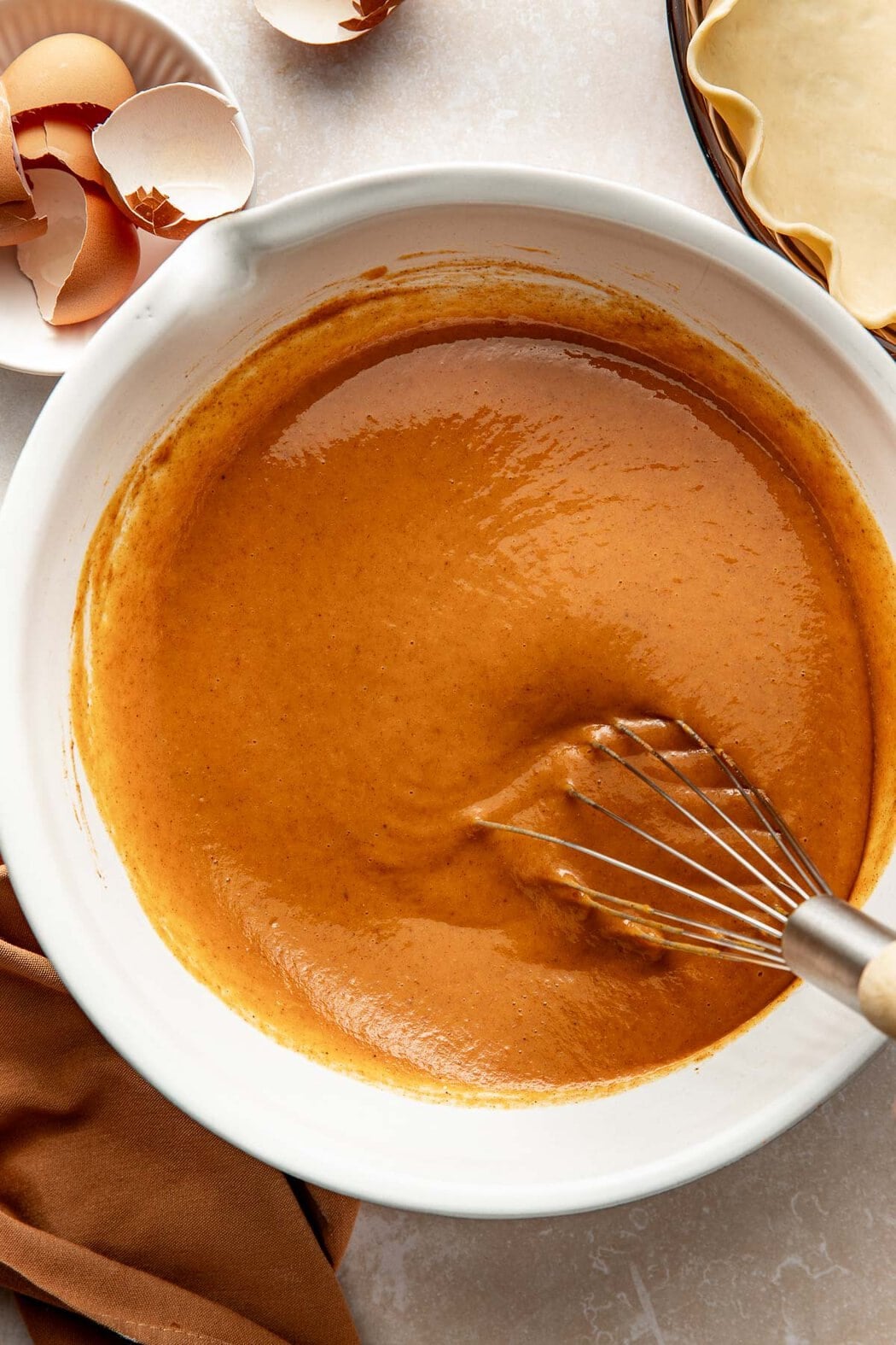 Pumpkin pie filling being whisked in a bowl.