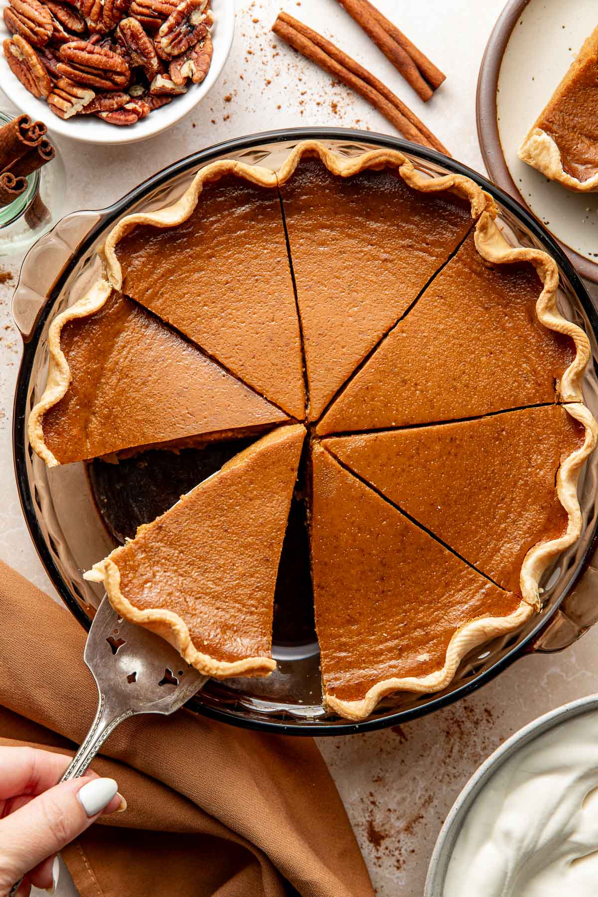 A pumpkin pie sliced into 8 pieces, one slice being removed from the pan.