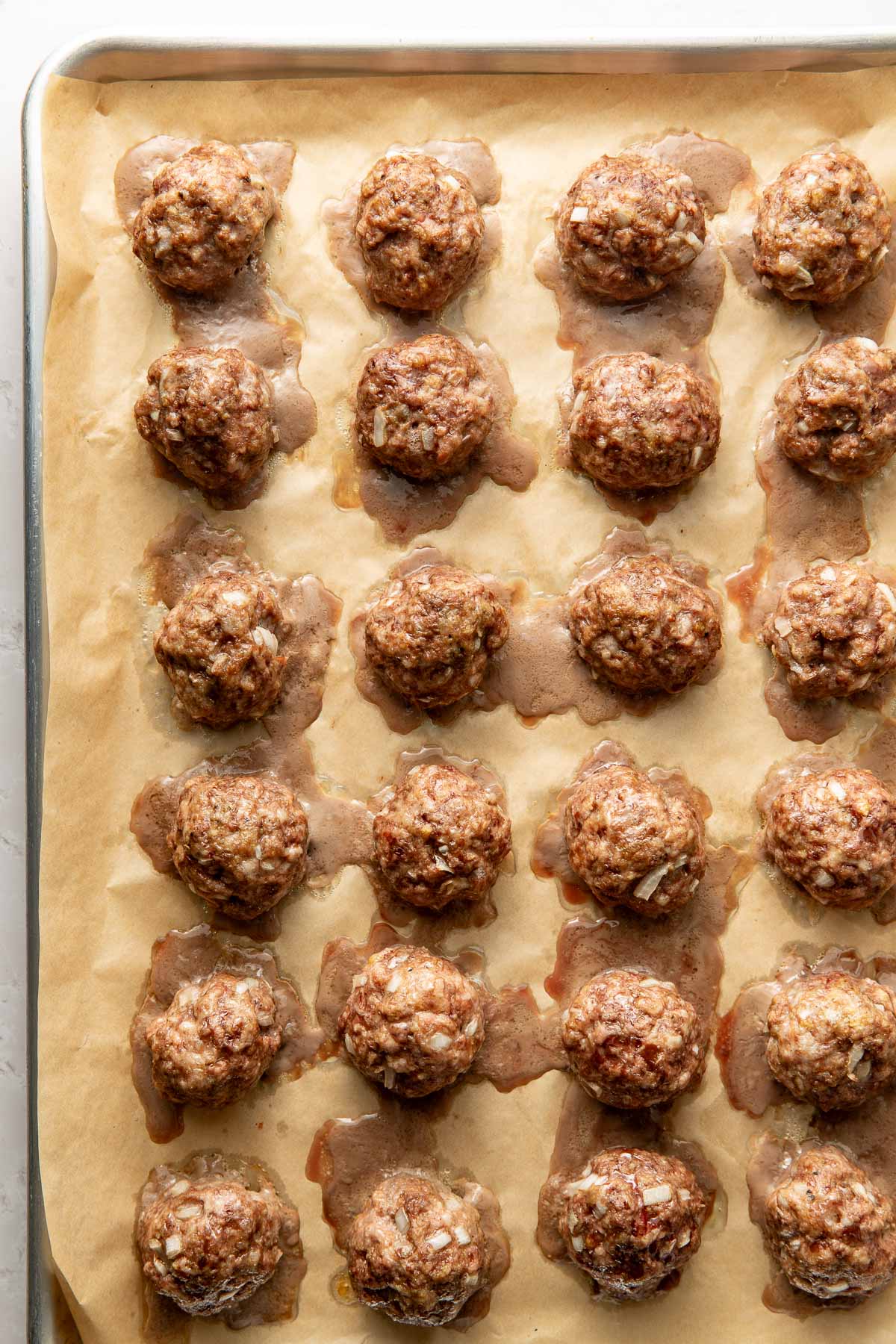 Baked Swedish meatballs on a parchment paper-lined baking sheet.