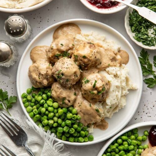 Swedish meatballs served over mashed potatoes with a side of peas.