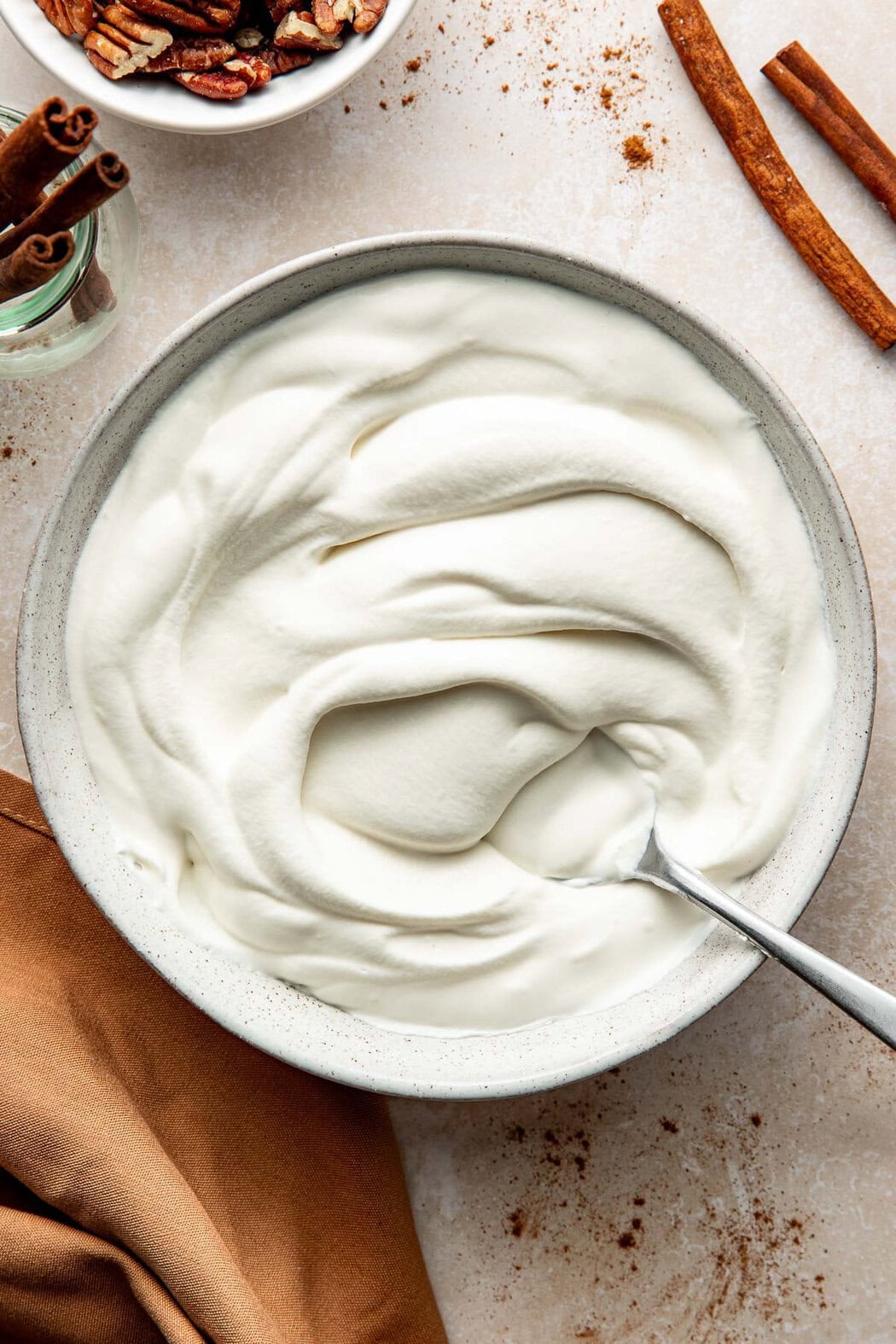 A bowl of homemade whipped cream with a spoon sticking out.