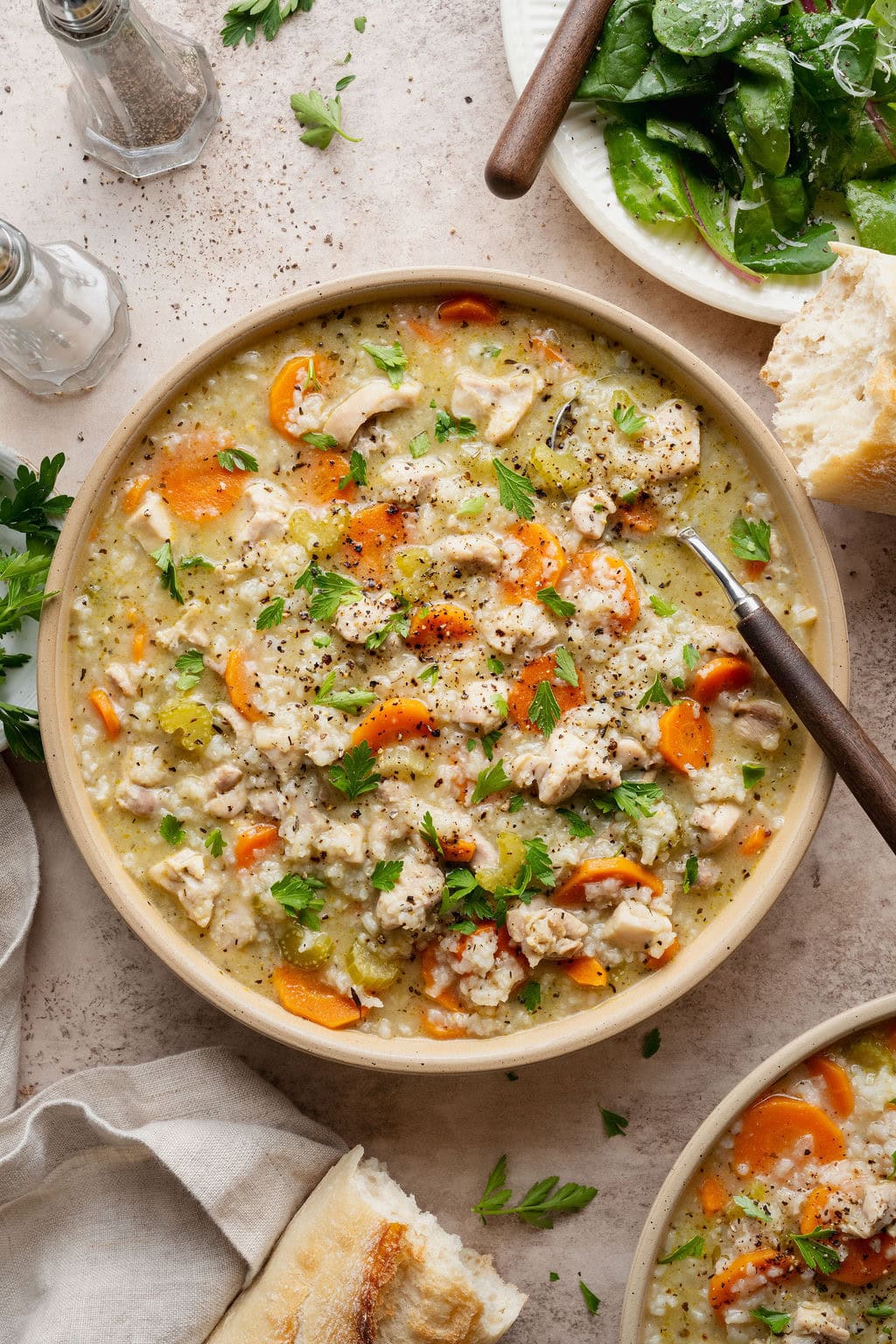 A bowl of chicken and rice soup with a spoon sticking out.