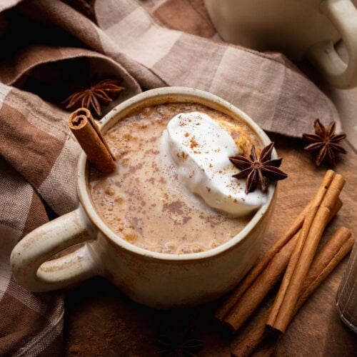 A pumpkin chai latte with a cinnamon stick sticking out.